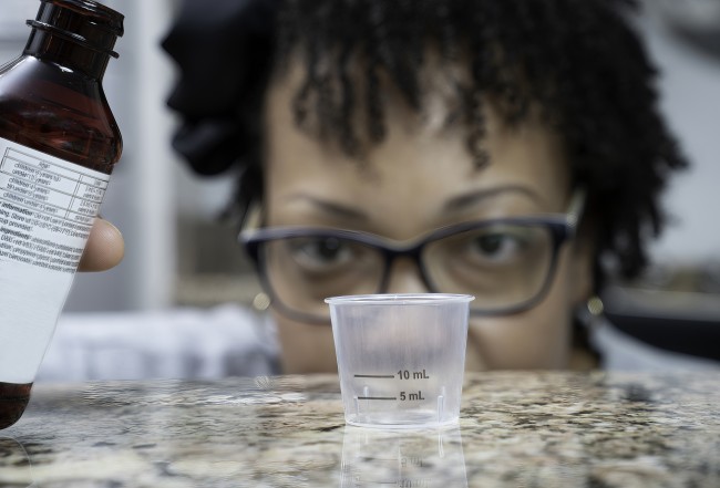 African American/Black woman measuring liquid medicine