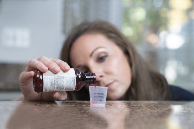 Caucasian/White woman measuring liquid medicine