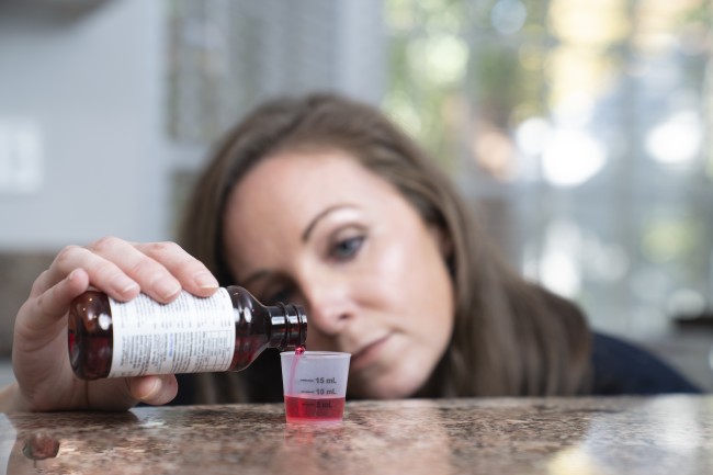 Caucasian/White woman measuring liquid medicine