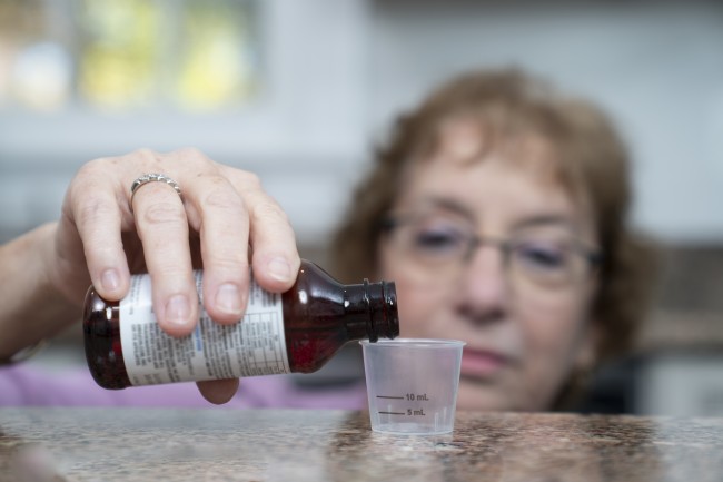 Caucasian/White woman with glasses measuring liquid medicine