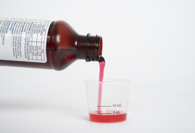 Liquid medicine being poured into a dosing cup