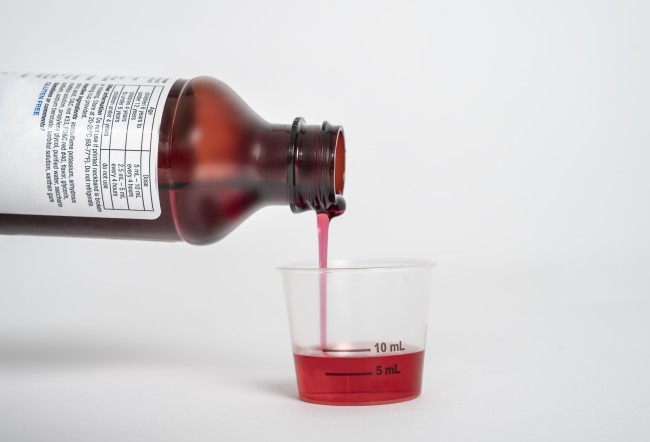 Liquid medicine being poured into a dosing cup