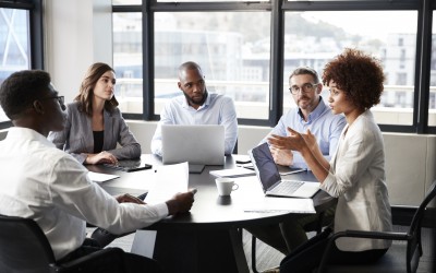 Millennial black businesswoman addressing colleagues at a corporate business meeting