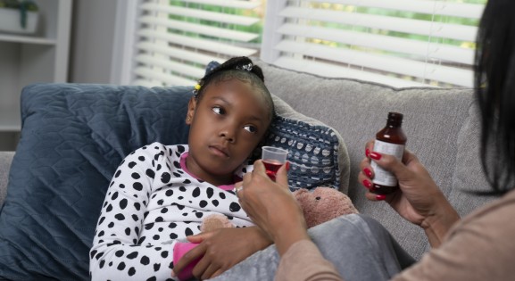 Woman giving sick girl medicine