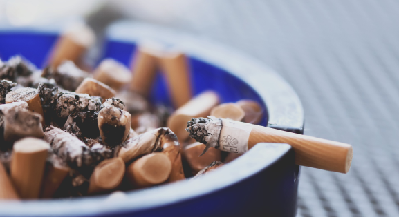 Cigarette Stubs in blue glass Ashtray